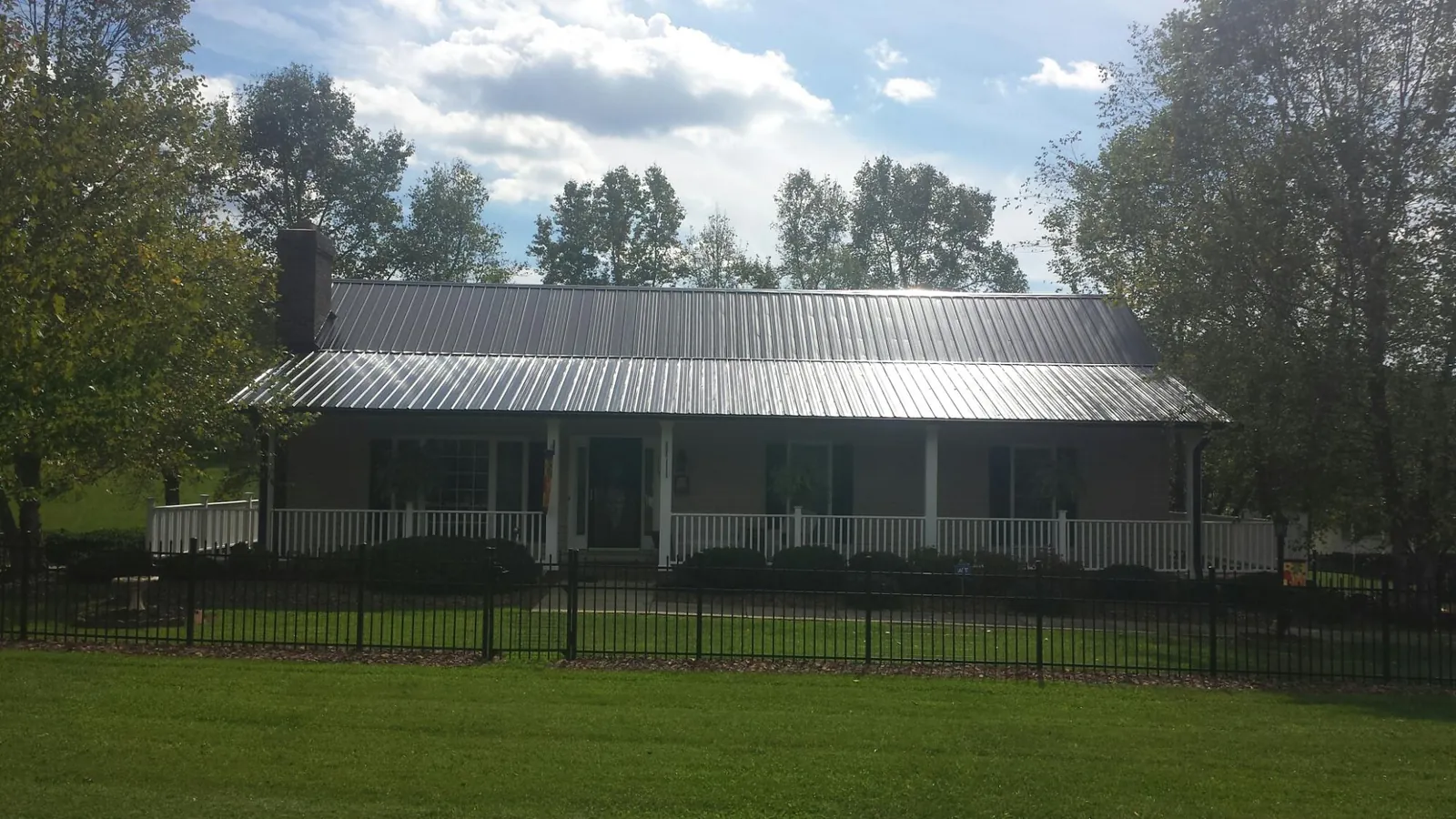 Gray metal roof on a brick ranch with a full width front porch — Gutter Guard Installation work by our crew in Belleville